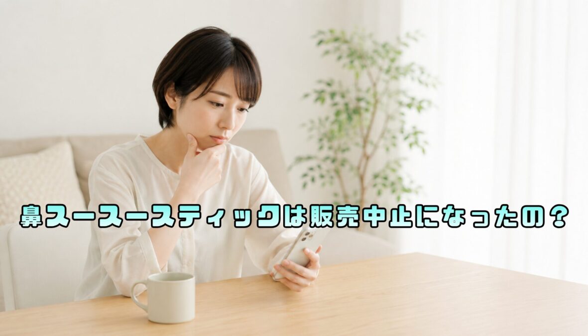 明るい室内の木製テーブルで、スマートフォンを見ながら顎に手を添えて考える女性
